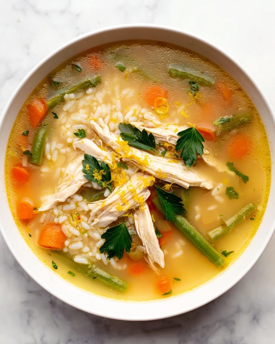 A white bowl is filled with a light yellow creamy soup containing white rice and small pieces of red and green vegetables. On top of the rice are several shredded pieces of light brown chicken and a few small green cilantro leaves. The soup is steaming hot, and there are tiny yellow zest sprinkles scattered on the surface. The bowl rests on a white marbled surface with a golden decorative line curving near one edge. photo taken with an iphone --ar 4:5 --v 7