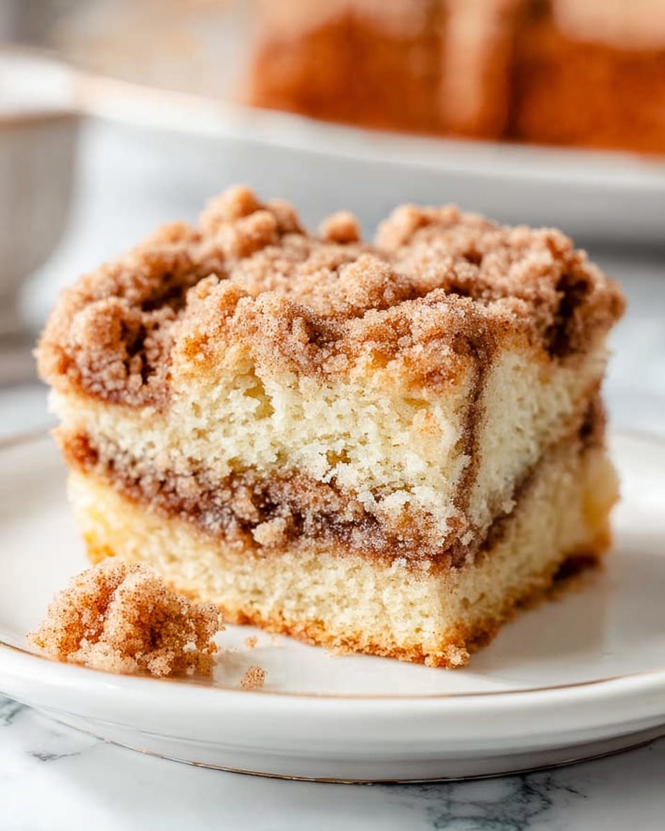 The image shows three square slices of crumb cake stacked with two layers of soft, light yellow cake and a dark brown middle layer of filling. The top layer is thick and crumbly with a rough texture in a golden brown color. Each piece sits on crumpled white parchment paper placed on a rough wooden surface, with a slight focus on the front slice. The lighting is soft and natural, highlighting the crumb topping and the cake's moist interior. photo taken with an iphone --ar 4:5 --v 7