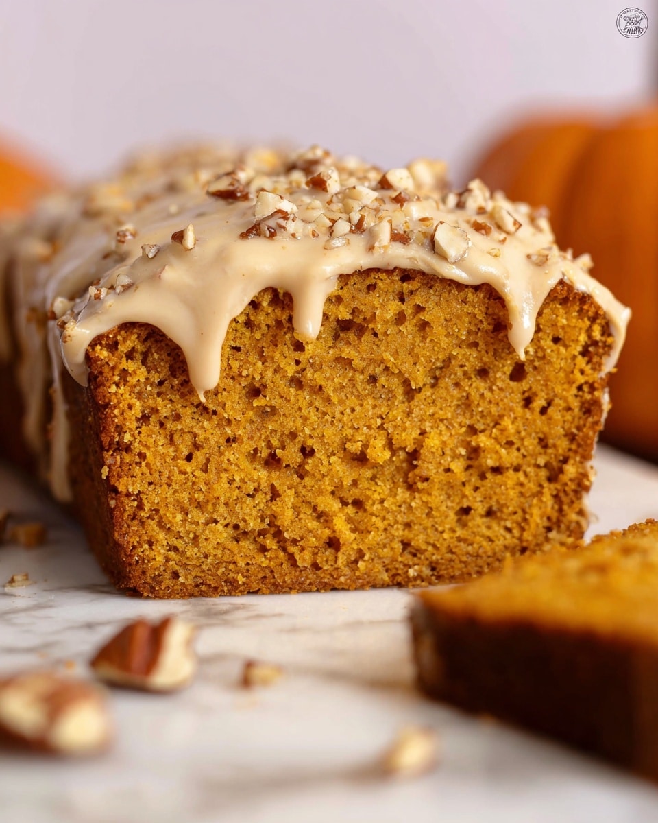 A close-up view of a single thick loaf cake with a deep brown base layer that looks moist and dense. The top layer has a chunky, crumbly texture made of small, uneven pieces in varying brown shades, resembling a nut and spice streusel topping. A light beige glaze is drizzled over the entire top surface, dripping down the sides in smooth, irregular streams. The cake sits on a metal cooling rack, placed on a white marbled surface. In the background, a blurred section of a pumpkin and a white-and-orange striped cloth can be seen. photo taken with an iphone --ar 4:5 --v 7