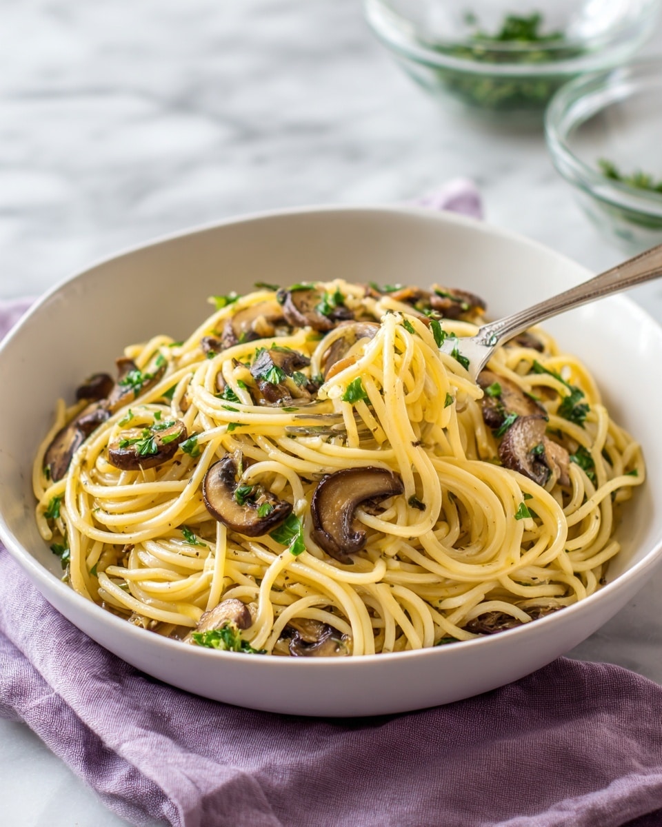 A white bowl sits on a soft lavender cloth with a small pile of spaghetti inside, showing about two main layers of long, light yellow noodles twisted around a silver fork lying in the bowl. Scattered throughout the pasta are browned slices of mushrooms, adding a darker brown color and soft, slightly textured feel. Small pieces of bright green parsley are mixed in, giving fresh spots of color on top of the noodles. The noodles appear lightly coated with oil or sauce, giving them a slightly shiny look. The background is a smooth white marble surface with two blurred glass bowls holding ingredients in the distance. Photo taken with an iphone --ar 4:5 --v 7