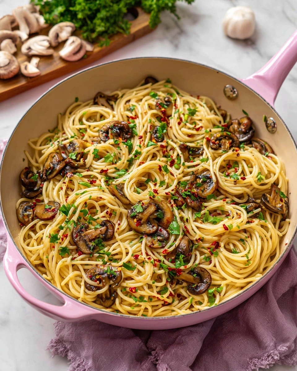 The image shows a pink skillet filled with a dish of spaghetti mixed with browned mushroom slices and sprinkled with green parsley leaves and small red chili flakes. The spaghetti is pale yellow and twisted throughout the pan, with the mushrooms dark brown and slightly shiny from cooking. The parsley adds pops of fresh green on top and inside the pasta. The skillet is placed on a white marbled surface with a light purple cloth under one side of the handle. In the background, a wooden board holds garlic cloves, sliced mushrooms, and a bunch of parsley, all blurred softly to keep focus on the pasta dish. photo taken with an iphone --ar 4:5 --v 7