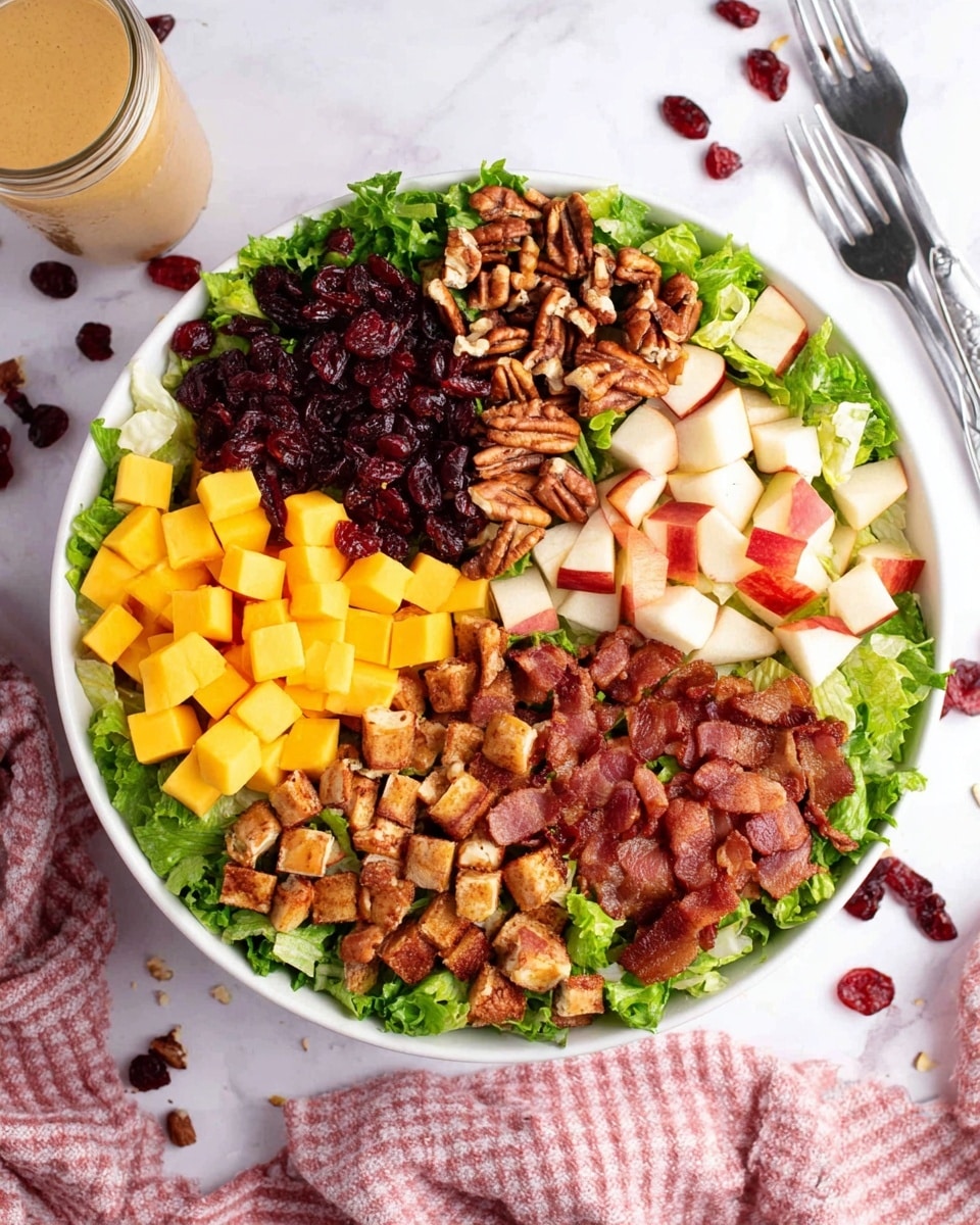 A white bowl filled with a fresh salad showing five distinct layers arranged side by side on a bed of green leafy lettuce; starting with dark red dried cranberries with a slightly wrinkled texture, followed by small orange-yellow cubes of cheddar cheese, next a pile of chopped light brown pecans with rough edges, then a section of small, white and red pieces of pear with smooth skin, and finally, crispy reddish-brown bacon bits with a slightly oily surface. The bowl sits on a white marbled textured surface. photo taken with an iphone --ar 4:5 --v 7