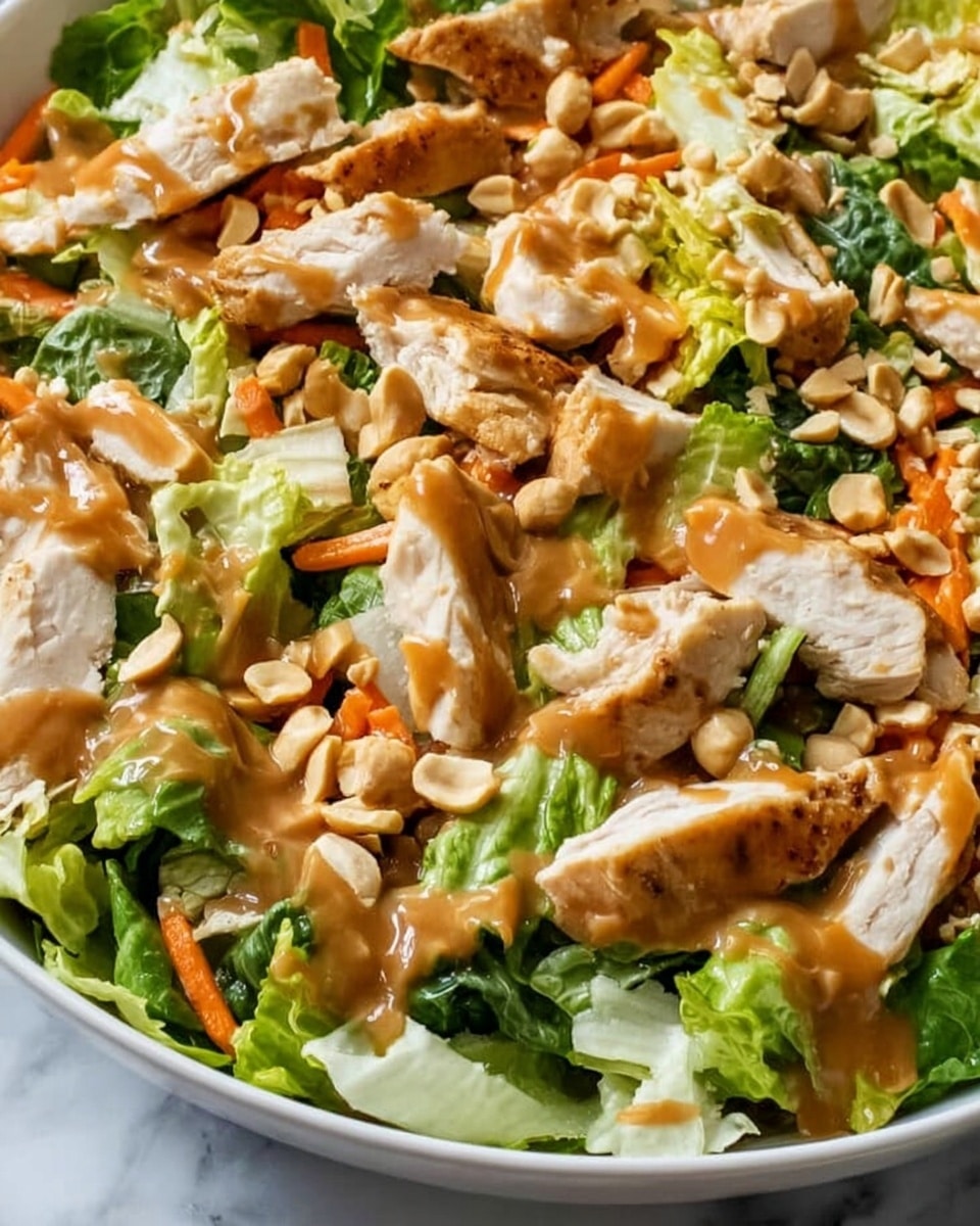 The image shows a white bowl filled with a colorful salad placed on a white marbled surface. The salad has several layers: the bottom layer is fresh green lettuce leaves, followed by a mix of shredded purple cabbage and thin orange carrot strips. On top, there are pieces of grilled chicken with a light brown, slightly glazed texture. Scattered over the salad are sliced green onions and toasted almond slices adding a crunchy look. The whole bowl has a fresh and vibrant appearance, with a smaller white bowl of almond slices in the background. Photo taken with an iphone --ar 4:5 --v 7