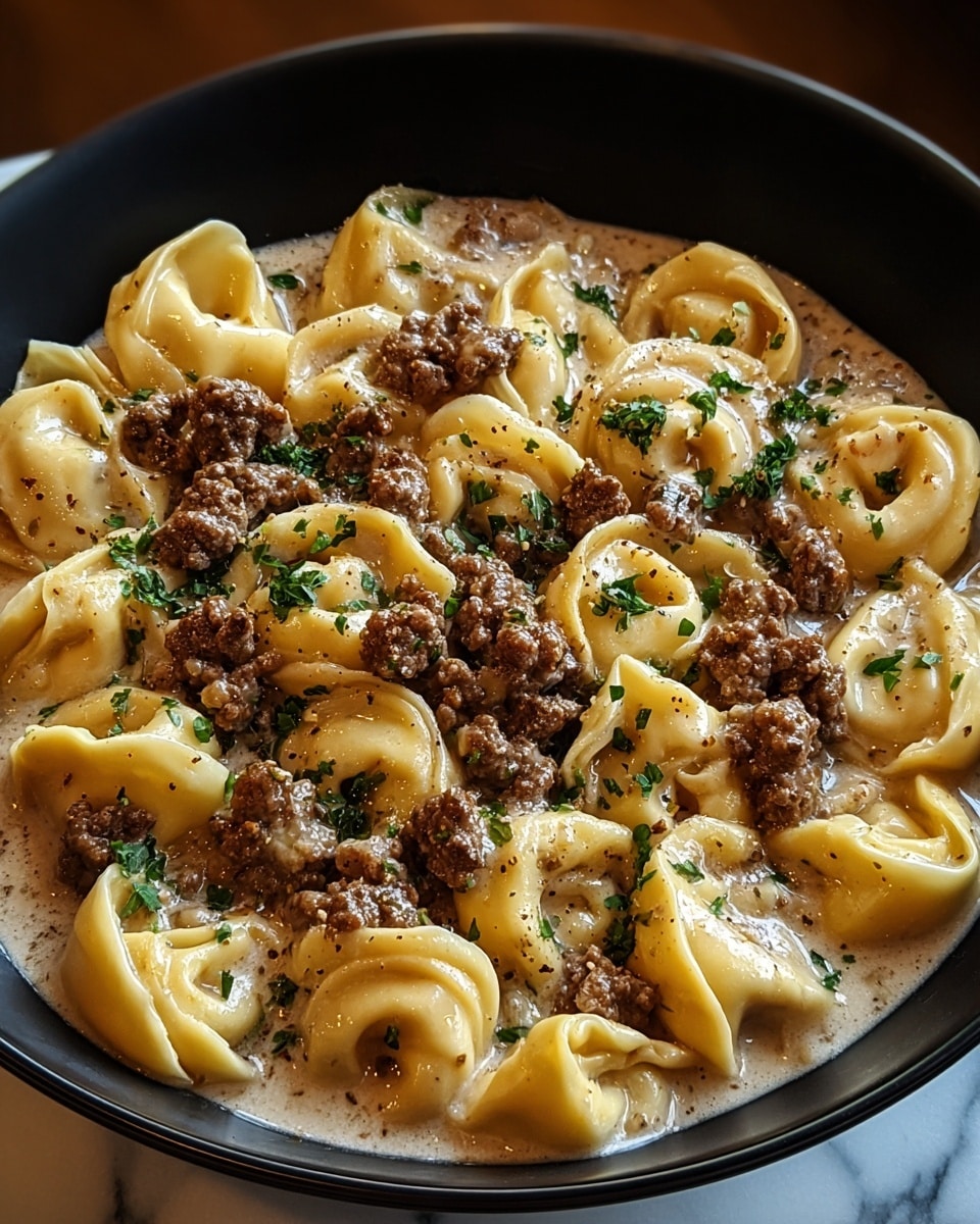 A black bowl filled with a creamy sauce base that has a light brown color and silky texture, layered evenly at the bottom. On top, there are about two layers of cooked tortellini pasta, each piece plump and smooth with a pale yellow color. Between the pasta pieces, there are generous chunks of browned ground meat scattered throughout, giving a rich, textured contrast. A sprinkle of fresh green herbs is spread over the dish, adding a pop of color and freshness. The bowl is placed on a white marbled surface, and the image captures the dish closely with warm lighting. photo taken with an iphone --ar 4:5 --v 7