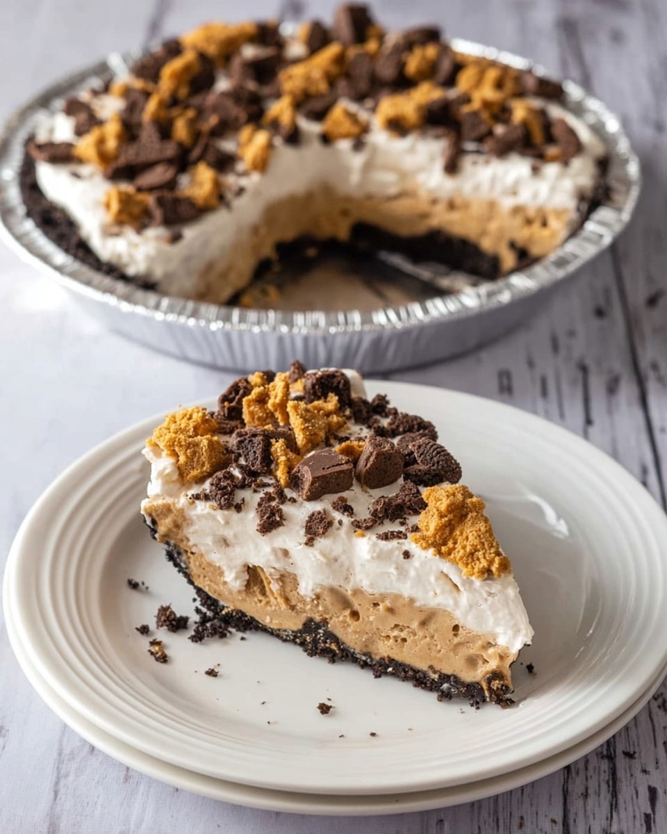 A slice of creamy pie is on a white plate with soft ridges, showing three layers: a dark chocolate crumb crust at the base, a thick light brown peanut butter or cookie dough middle layer, and a fluffy white cream top layer. The cream layer is sprinkled with large chunks of dark brown chocolate cookies and golden crumbled cookie pieces. Next to the plate is the rest of the pie in a round, silver foil dish, missing the slice. The pie looks soft and rich, and the white marbled surface underneath adds a clean, bright background. photo taken with an iphone --ar 4:5 --v 7