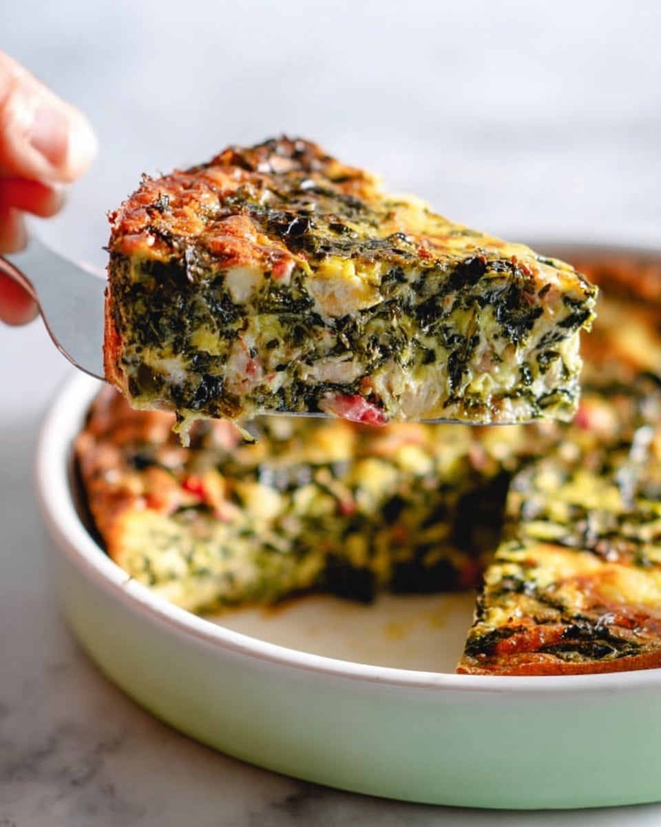 A slice of a baked dish is being lifted from a white round baking dish with a silver spatula held by a woman's hand. The dish has three visible layers: the bottom crust is golden brown and slightly crispy, the middle layer is dense and mixed with green leafy vegetables and small red pieces, and the top layer is a light, slightly browned cheese or egg mixture with visible textures from the greens. The background is a white marbled surface with soft lighting highlighting the colors and textures of the food. Photo taken with an iphone --ar 4:5 --v 7