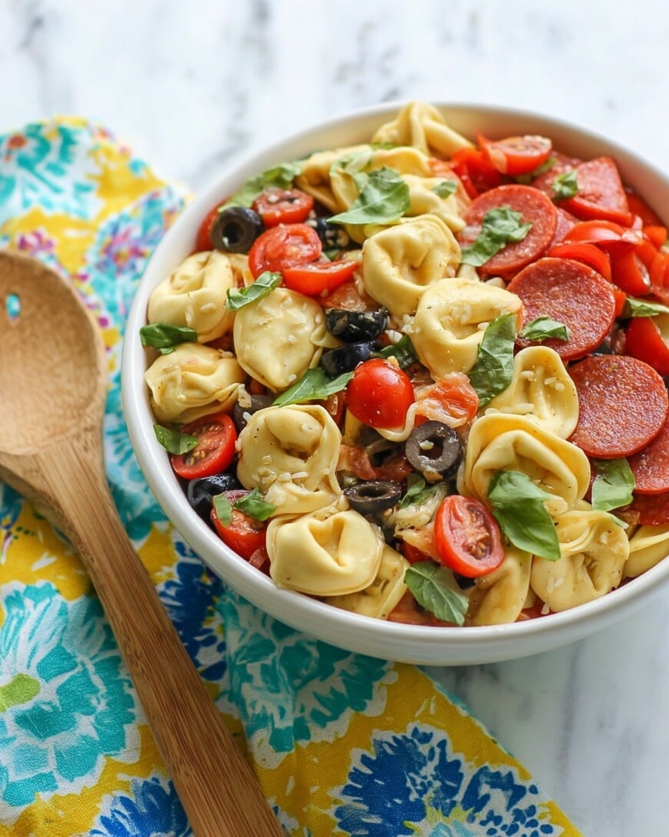 A white bowl filled with three layers: the bottom layer is yellow tortellini pasta with a soft, smooth texture, the middle layer contains sliced red cherry tomatoes and small round slices of pepperoni, the top layer is sprinkled with fresh green basil leaves and black olive slices, creating a colorful and fresh look; the bowl is placed on a white marbled surface with a wooden salad fork and a multicolored cloth napkin beside it. photo taken with an iphone --ar 4:5 --v 7