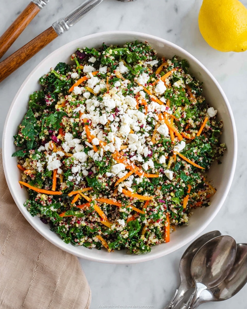 A large white bowl sits on a white marbled surface filled with a mixed salad featuring multiple layers: a base of finely chopped dark green kale leaves, then light-colored quinoa mixed in, topped with thin, bright orange carrot strips scattered throughout, and finished with small, uneven white crumbles of feta cheese spread across the top. To the side of the bowl are silver serving spoons with wooden handles, and a yellow lemon is partially visible near the top left. Photo taken with an iphone --ar 4:5 --v 7